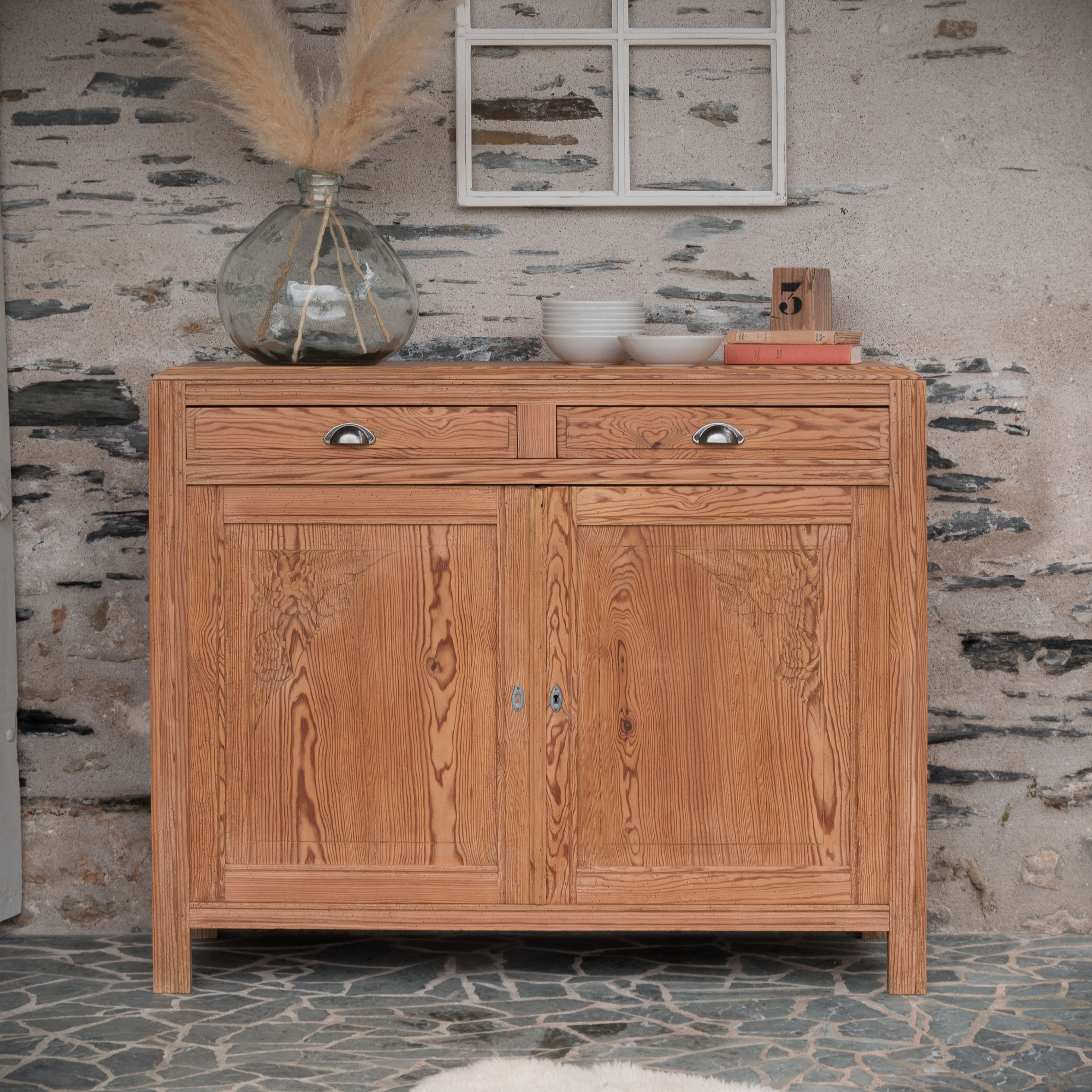 Photo d’un buffet Art Déco en sapin massif rénové, avec tiroirs et portes gravées, placé dans un décor rustique et chaleureux