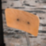 Ancienne chaise d’atelier pivotante en bois et métal, assise réglable, posée devant un mur en pierre.