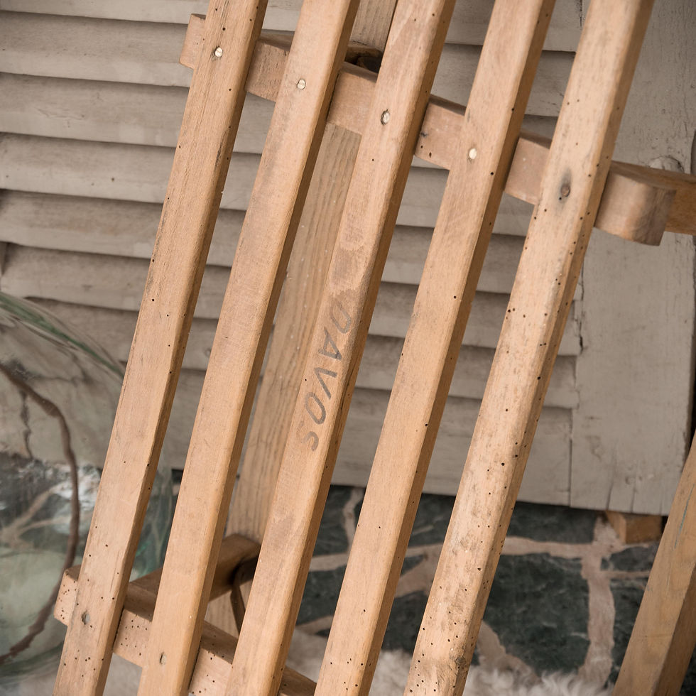 Ancienne luge Davos en bois vintage posée contre un mur en pierre dans une ambiance chalet gris groseille brocante en ligne