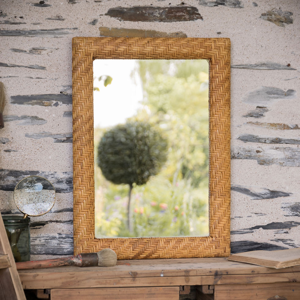 Miroir vintage rectangulaire en rotin tressé posé sur un établi ancien, décoration bohème naturelle et brocante chic.