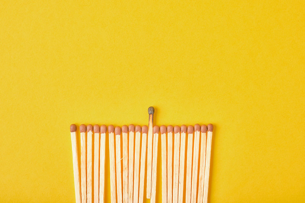Uitgebrande lucifer tussen ongebruikte lucifers, symbool voor burn-out en emotionele uitputting binnen een team