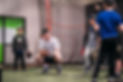 360U Baseball coach squatting down, teaching two baseball atheltes a drill.