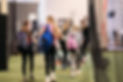 360U athletes smiling at one another they are walking with their softball bags and equipment.