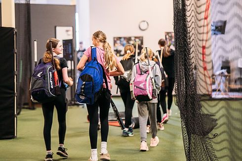 360U athletes smiling at one another they are walking with their softball bags and equipment.
