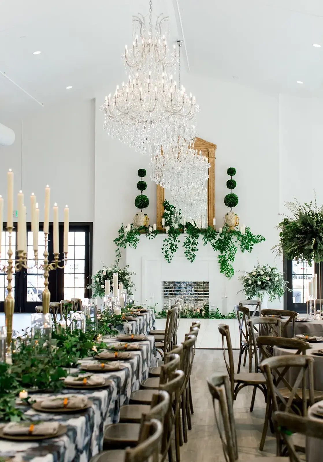 The dining room set up with chandeliers and greenery. 
