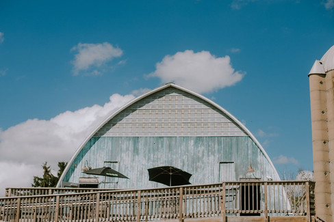 The outside of Poplar Creek Barn. It is a bluish/green barn with a handicapped railing leading to it.