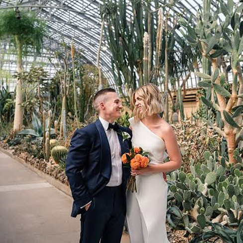 A bride and groom smiling at each other surrounded by dessert plants at Garfield Park Conservatory, a Chicago wedding venue