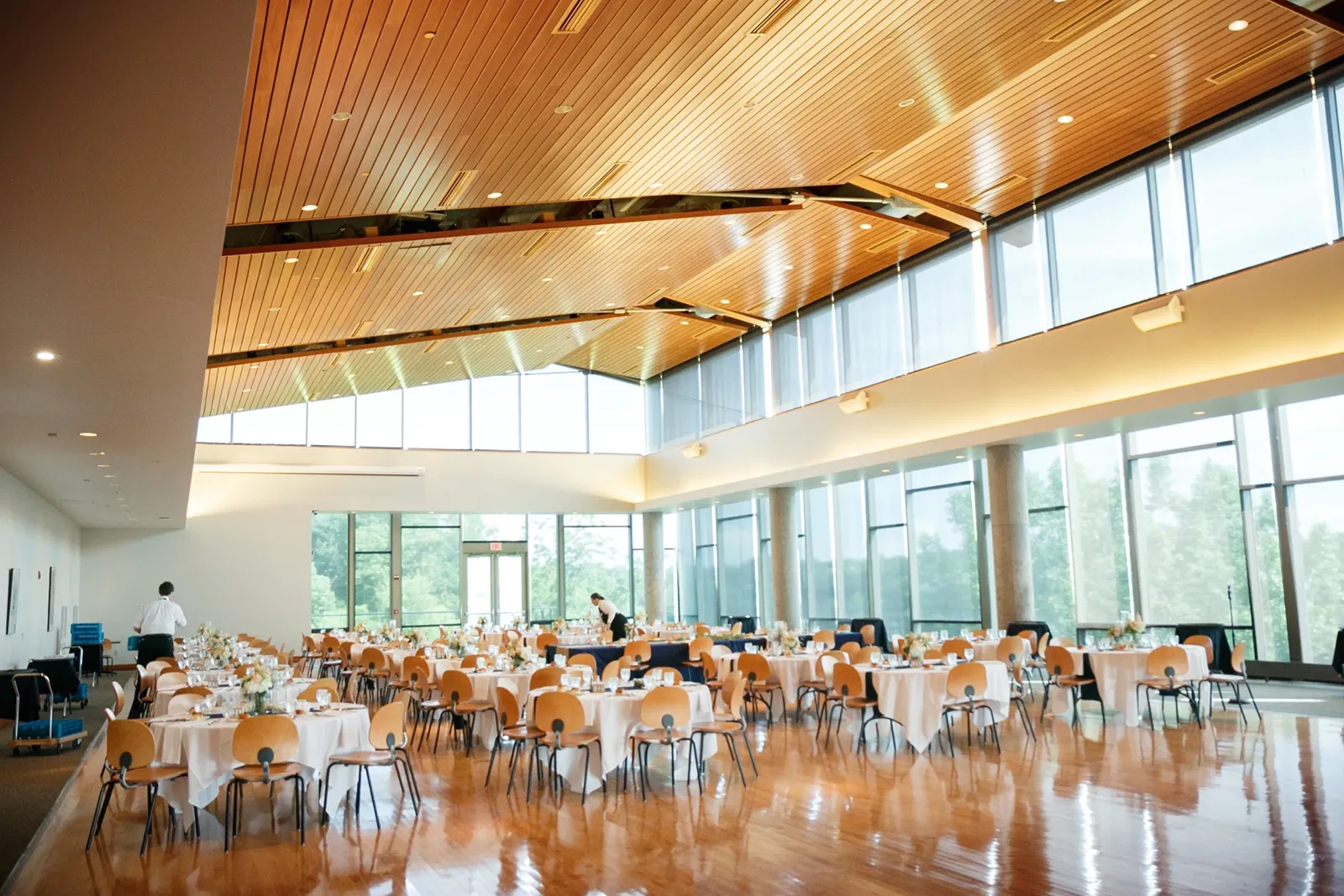 A lofty and sunny dining room with large windows and set up for dinner.