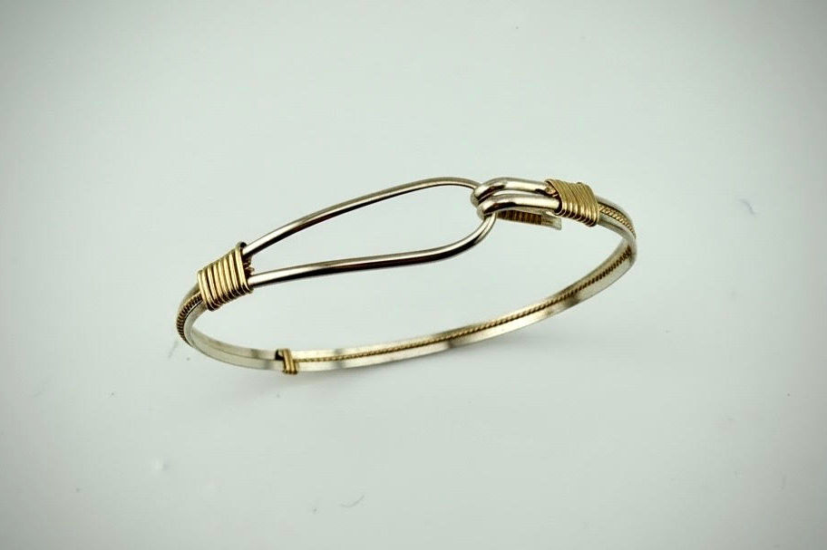 Hooked Bracelet standing upright displaying slender sterling silver and rolled gold bracelet design