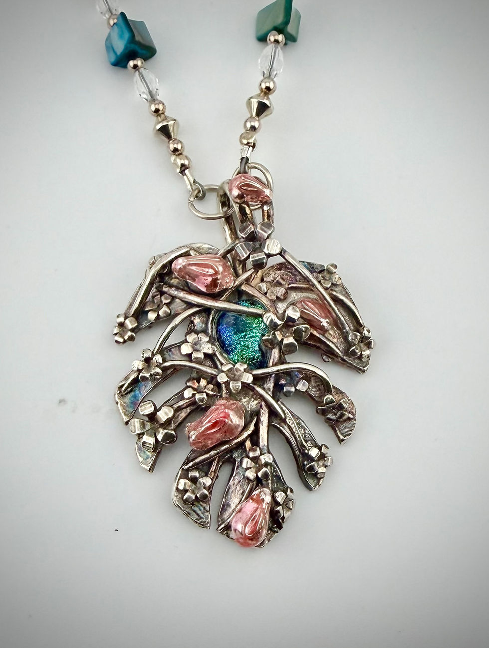 Full view of Looking For Rabbits necklace with blue Howlite beads, silver pendant, and whimsical pink rabbits