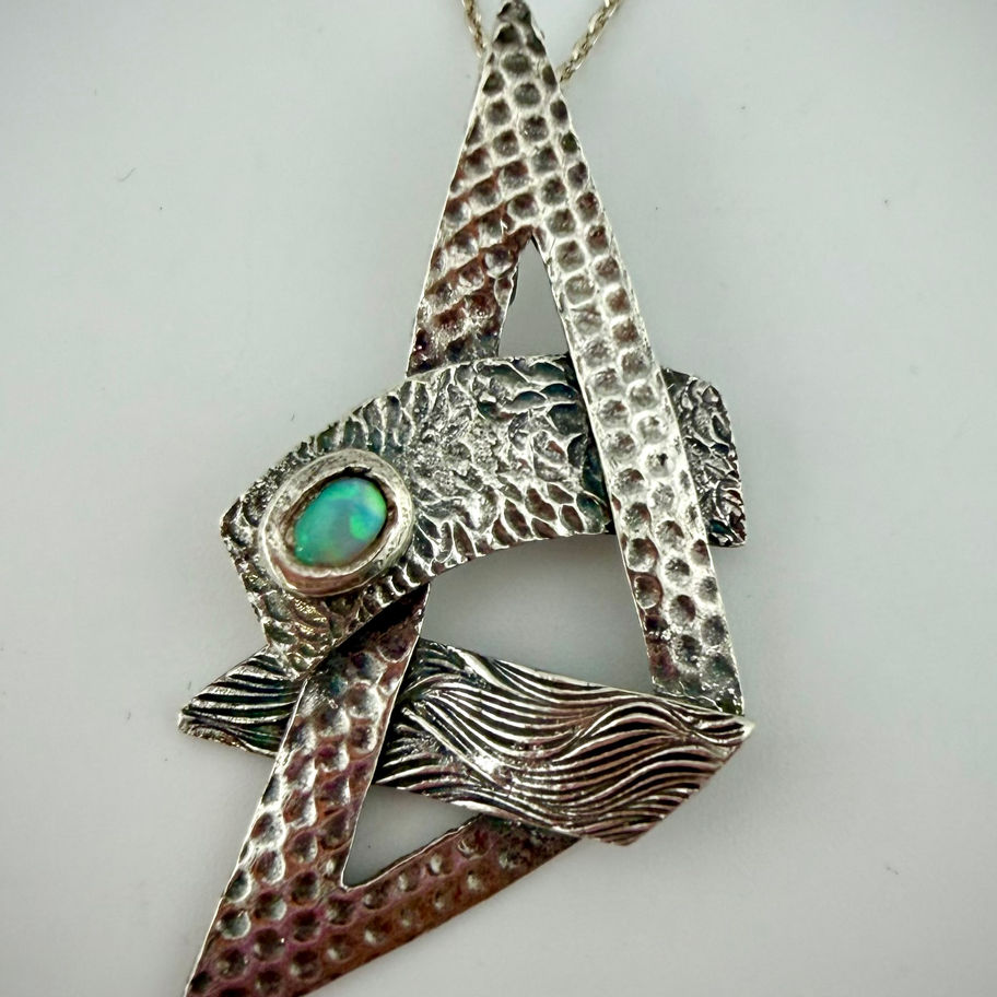 Close-up of Geometric Set 1 triangular pendant featuring green cultured opal and fine silver geometric design