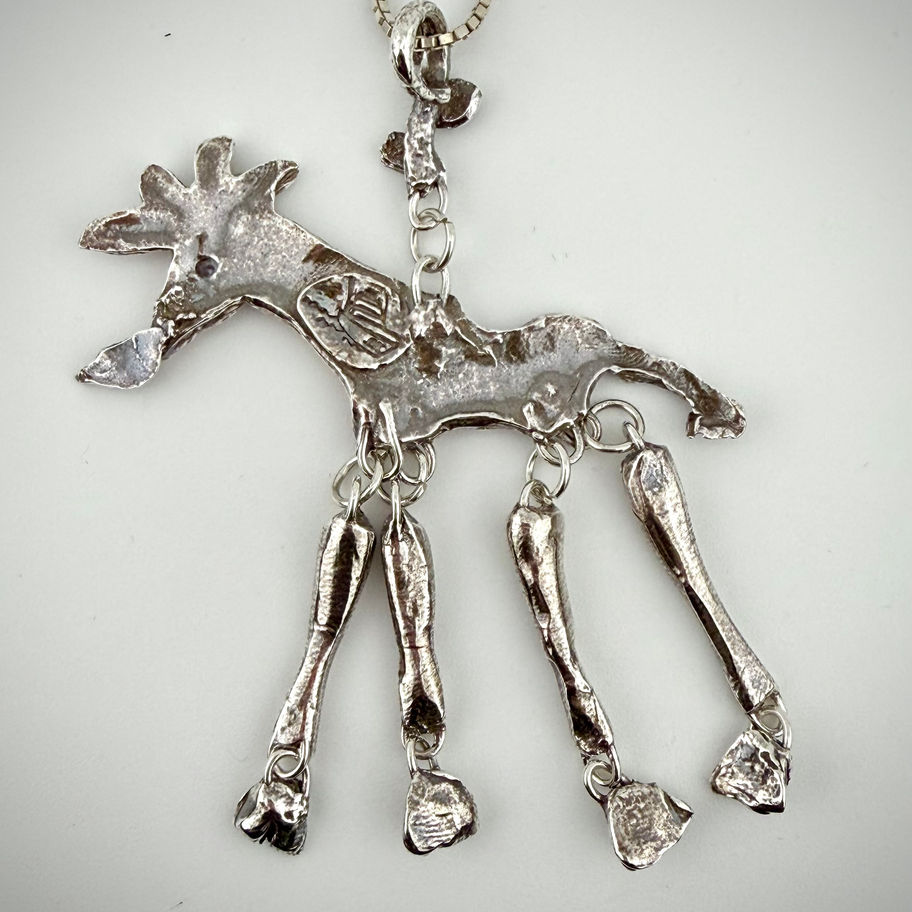 Front view of Hungry Giraffe pendant showing fine silver giraffe eating leaves with kinetic moving leg detail