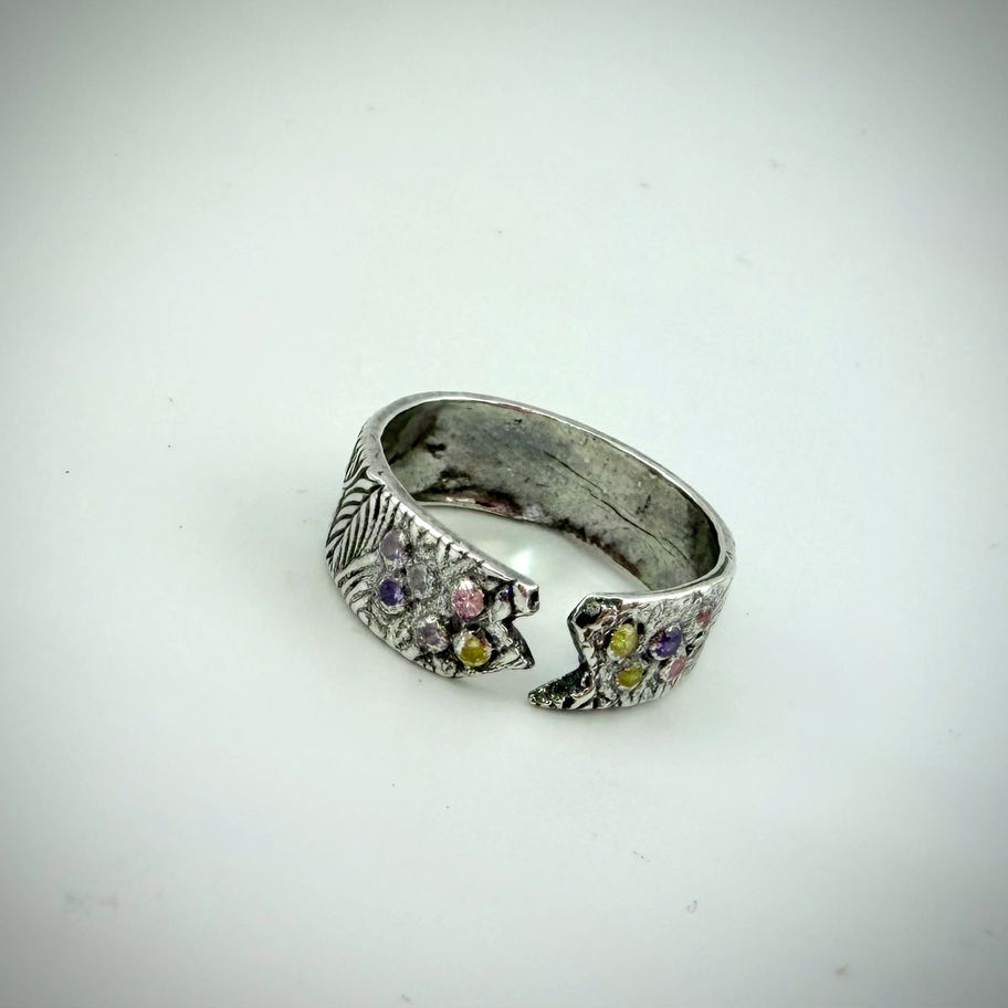 Right-angled front view of Open Zag Ring, displaying silver leaf details and vibrant CZ stones.