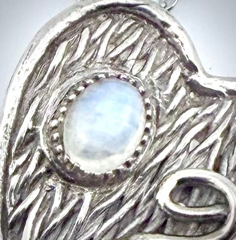 Close-up of Moonstone and Swirls heart-shaped pendant highlighting rainbow moonstone and detailed silver dotted setting.