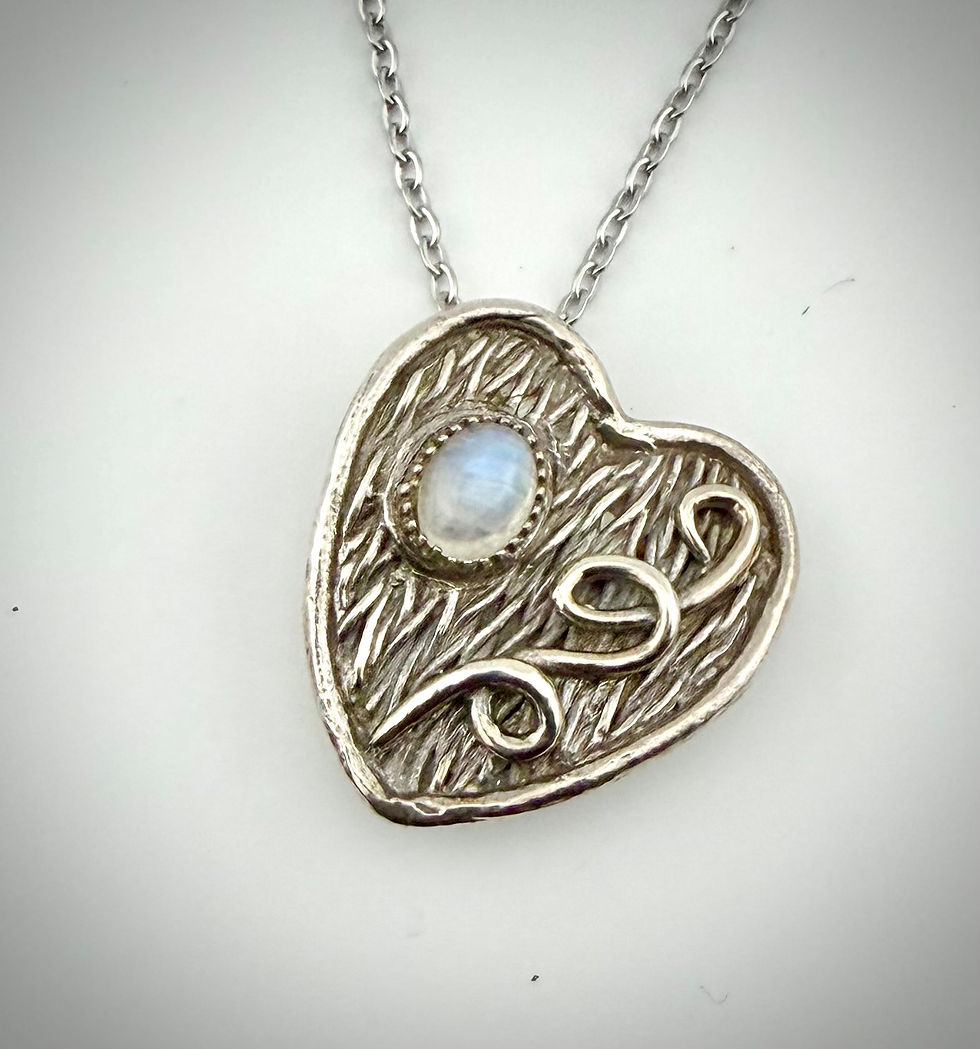 Front view of Moonstone and Swirls heart-shaped pendant featuring rainbow moonstone, textured silver swirls, and detailed set