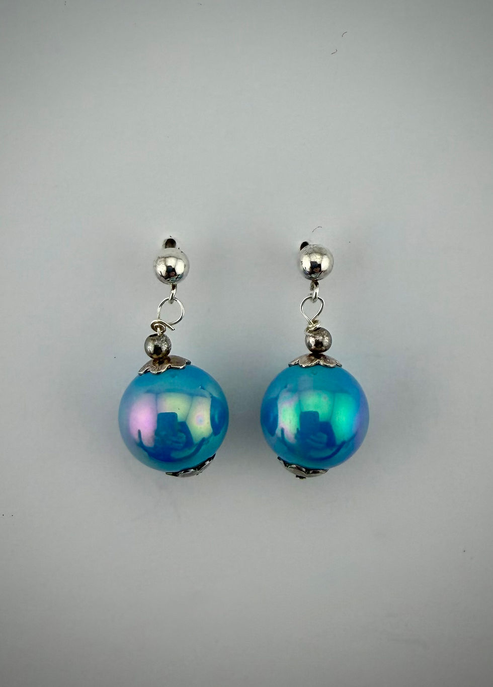 Front view of blue Majorca pearl silver bead cap post earrings highlighting iridescent pearl and polished silver