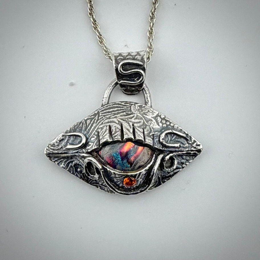 Front view of Eye See You #3 dichroic glass pendant with vibrant orange cabochon and whimsical swirls.