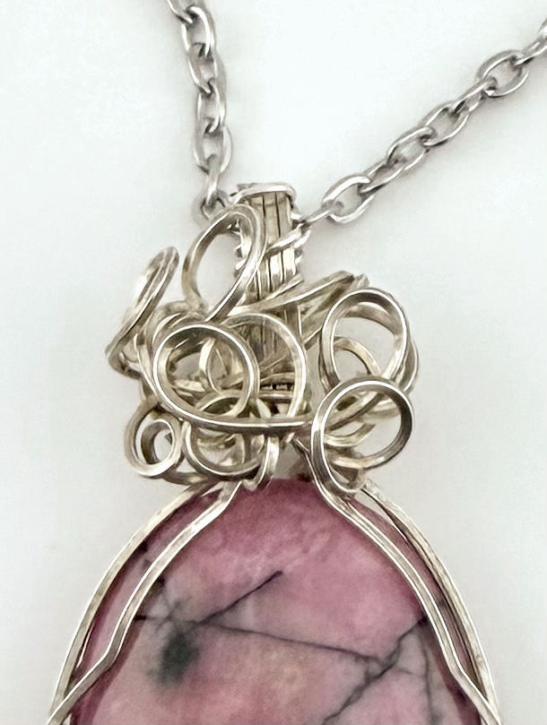 Close-up of Rose Pendant showing Rhodonite stone with intricately hand wire-wrapped sterling silver bail.