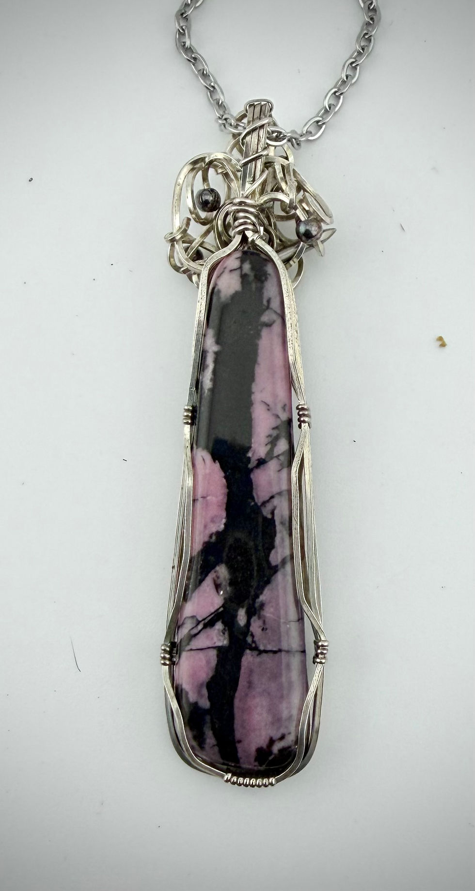 Back view rhodonite pendant with sterling silver wire wrapping, highlighting smooth stone backing and handcrafted structure