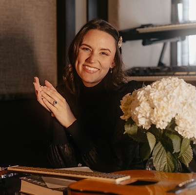 Rebekah Powell, award-winning songwriter and master life coach, smiles in front of piano and guitar on the rhythm of joy retreat for women in nashville
