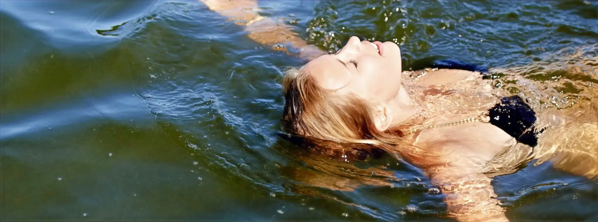 In the pleasant Castelo de Bode Lake in Ferreira do Zêzere, Portugal, a woman sways in the water.
