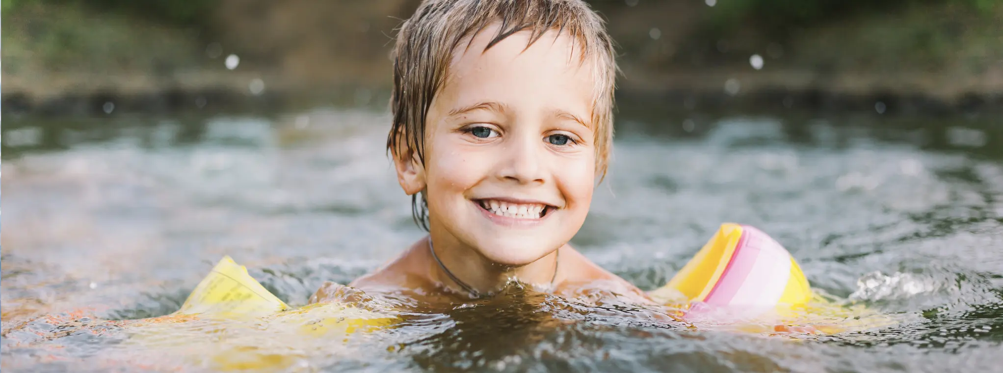 A child swims in the clear, warm water of Castelo de Bode Lake in Ferreira do Zêzere, Portugal.