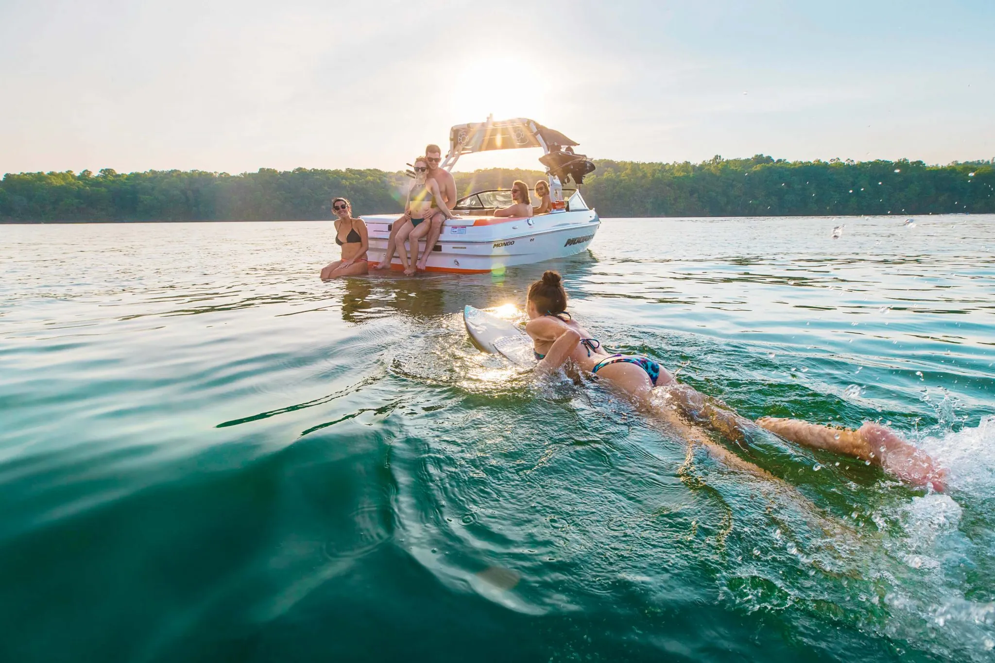 A young woman paddles to a boat with friends having fun at castelo de bode lake clear waters in the summertime
