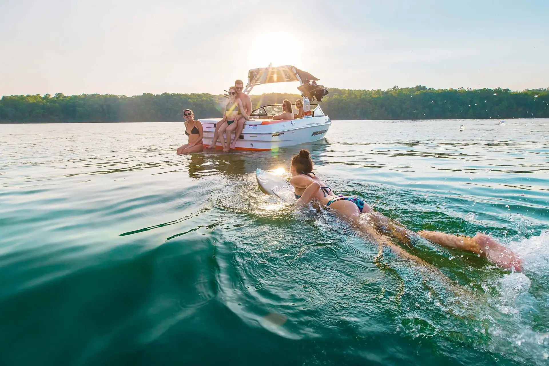 A young woman paddles to a boat with friends having fun at castelo de bode lake clear waters in the summertime