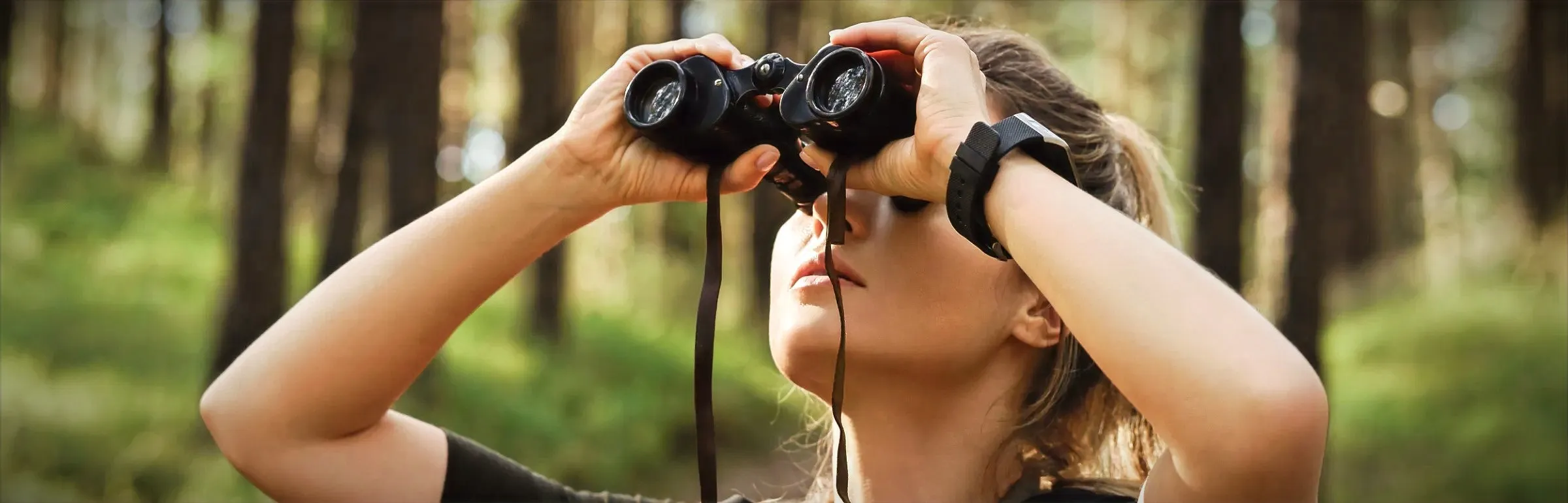 A young woman uses binoculars to observe birds in Castelo de Bode Lake, Ferreira do Zêzere, Portugal