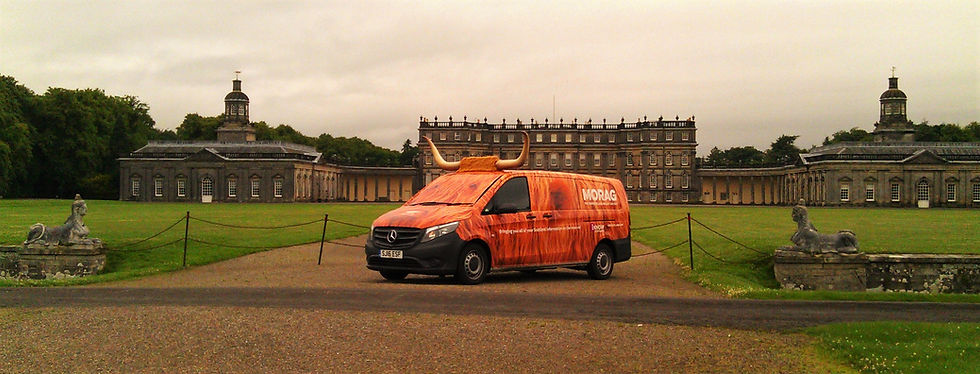 Morag the Visit Scotland highland coo van sitting in front of the grand Hopetoun House.