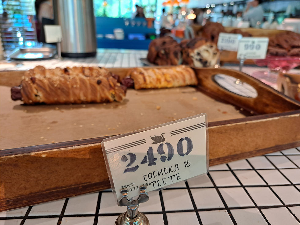 Bakery display with pastries on trays; front sign reads 2490 and ГОСТИНКА В ТЕСТЕ.
