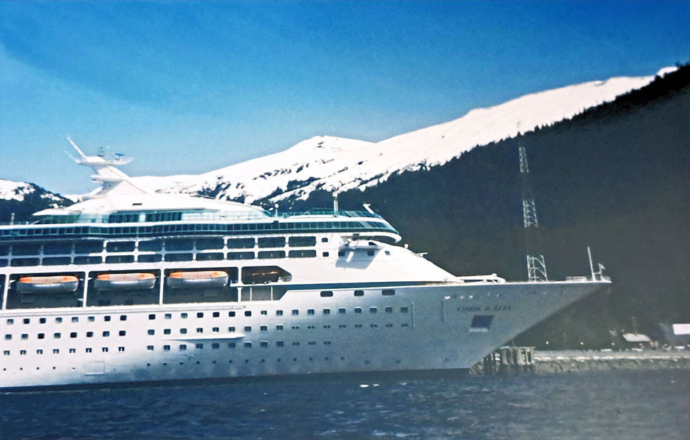 Large white cruise ship in blue water near snowy mountains under a clear blue sky, calm scenic harbor view