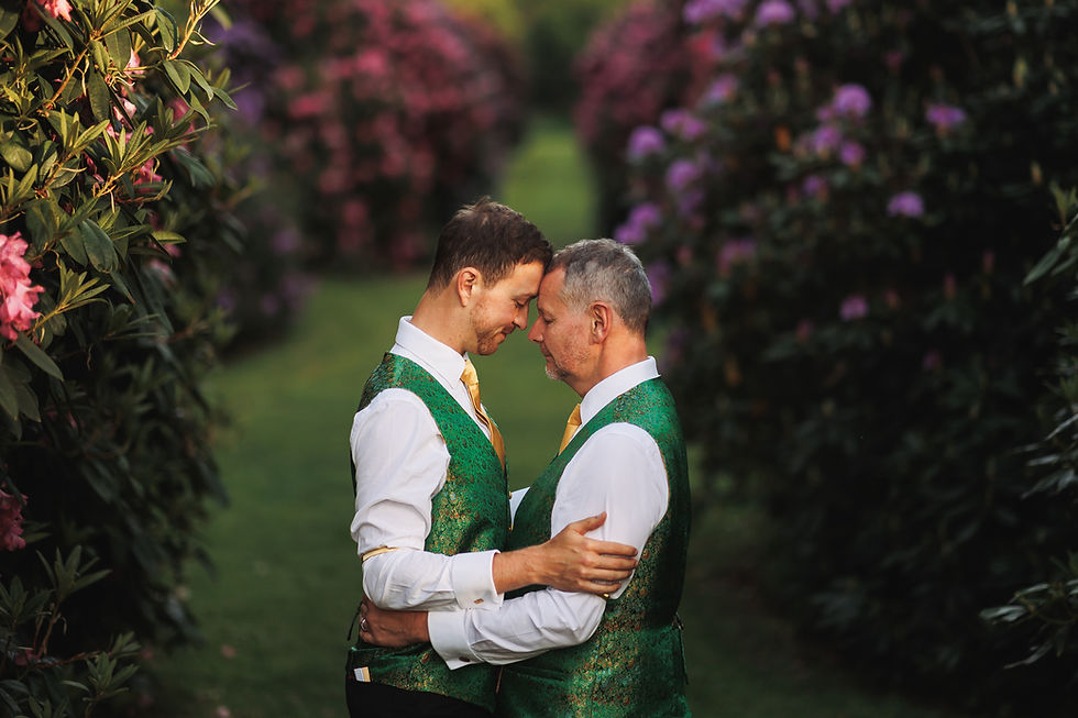 Gay age gap relationship couple hugging in an embrace in a garden wearing green suits