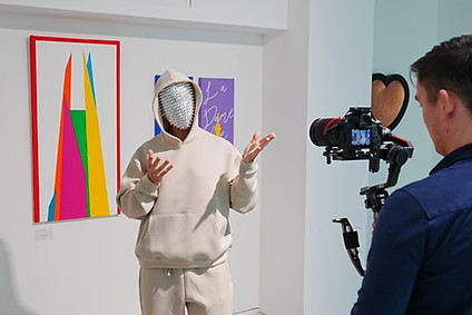 RECOGNITION discussing artwork while being filmed at a London exhibition