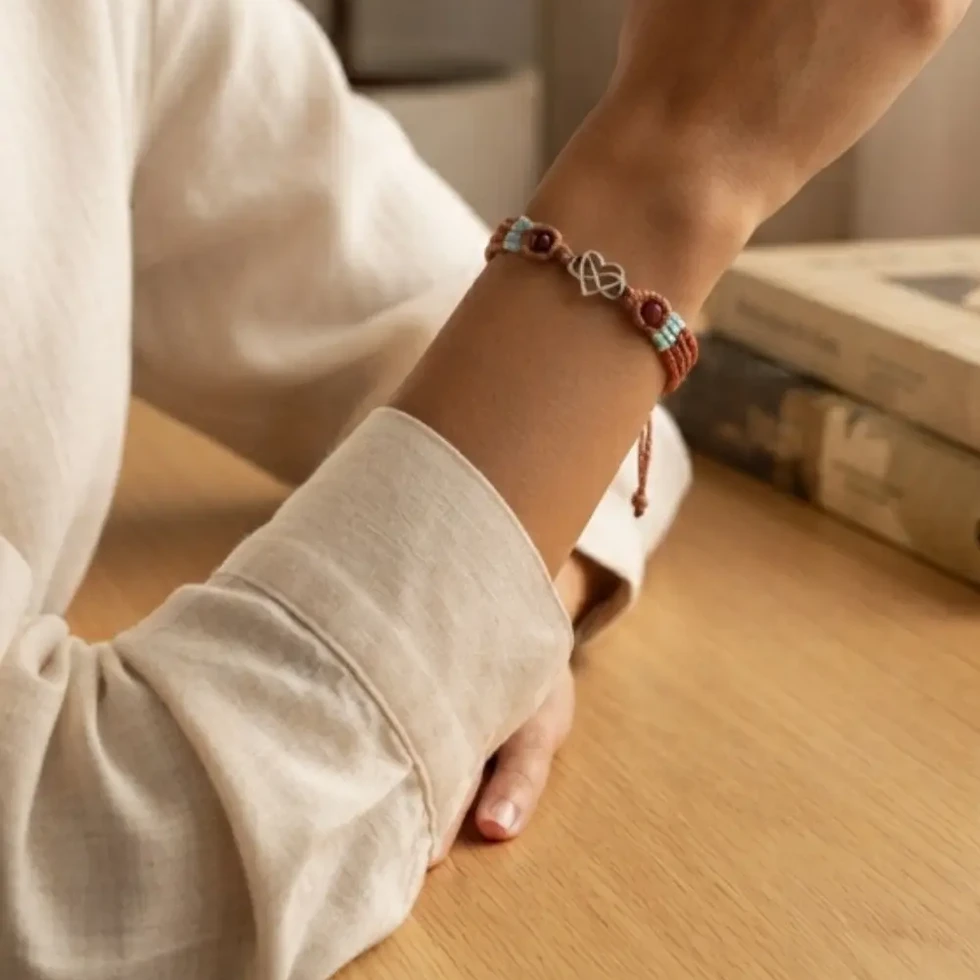 Bracelet Alya marron et turquoise en micromacramé avec un coeur enlacé et deux agathes porté au poignet
