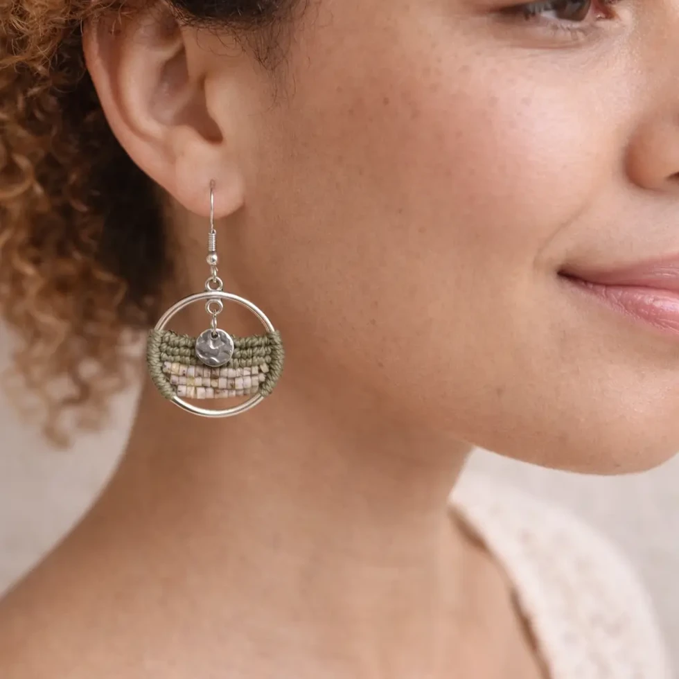 Femme portant les boucles d'oreilles Sélia Sauge avec un pampille argenté et un tissage macramé vert sauge
