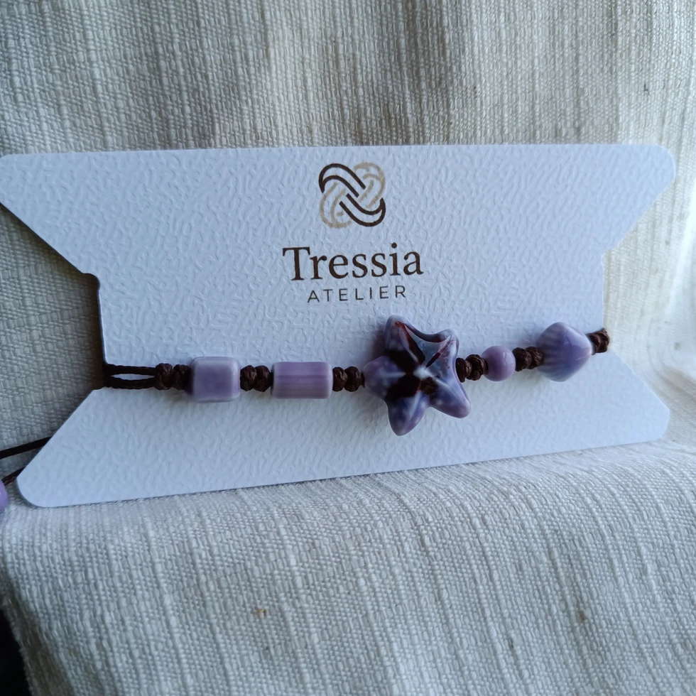bracelet macramé étoile porcelaine violet fait main tressia atelier sur carte produit fond tissu naturel