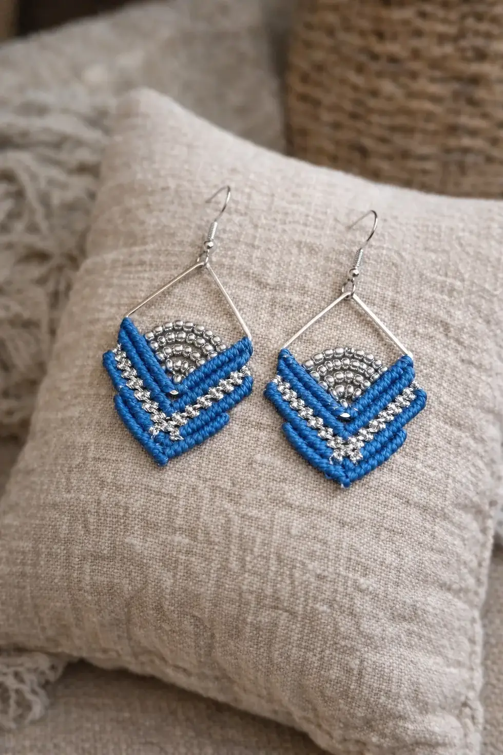 Gros plan des boucles d'oreilles ISO Cobalt en forme de losange, avec un tissage bleu intense et des perles argentées