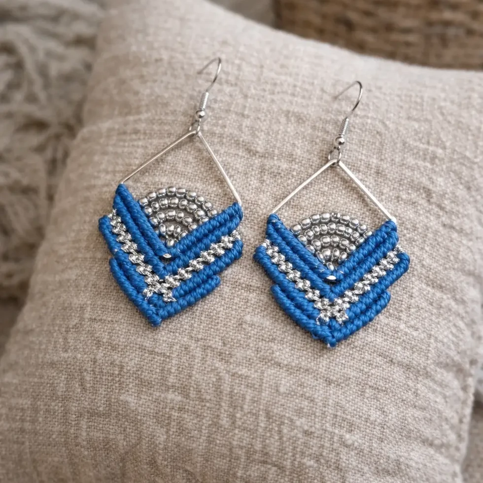 Gros plan des boucles d'oreilles ISO Cobalt en forme de losange, avec un tissage bleu intense et des perles argentées