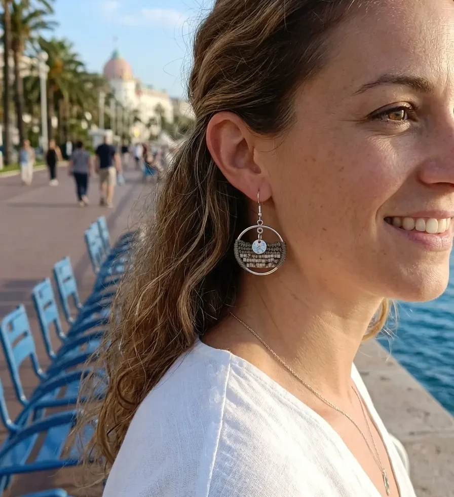 femme se promenant sur le bord de mer et qui porte les boucles artisanales Sélénia sauge avec des perles types nacre