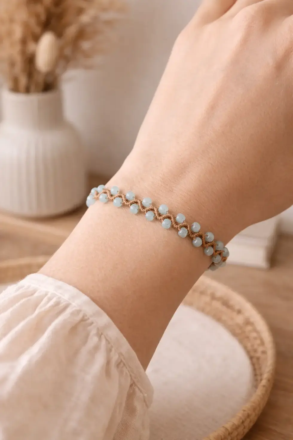 bracelet bohème en macramé sable avec perles œil de chat bleu clair – modèle Cattie au poignet