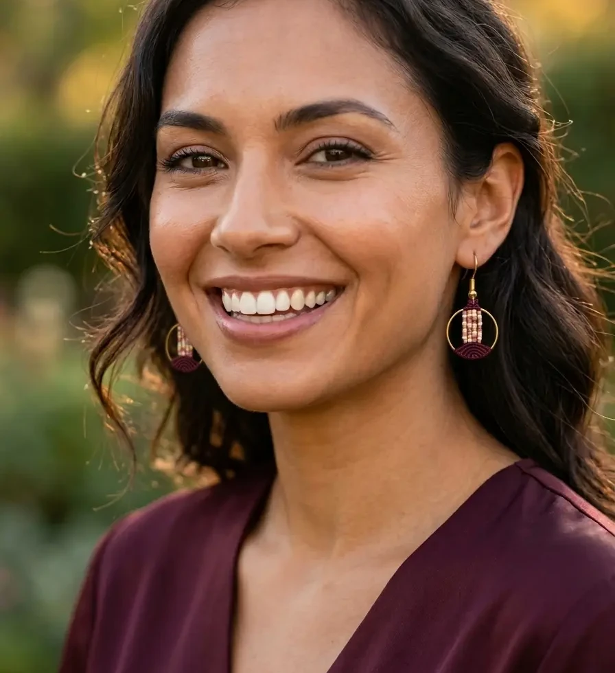 boucles d'oreilles lyren bordeaux en macramé artisanale portées par une jeune femme souriante