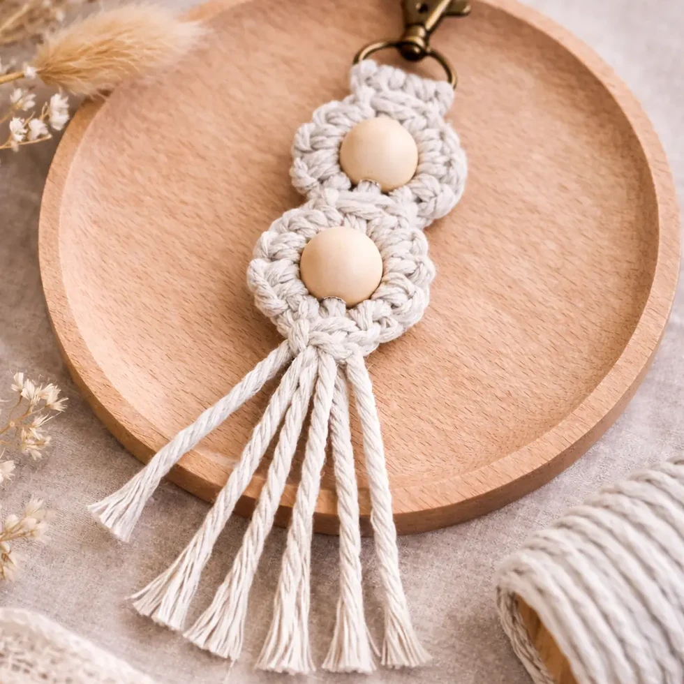 porte-clés Luna en macramé fait avec deux perles rondes en bois main de couleur lin sur un plat en bois