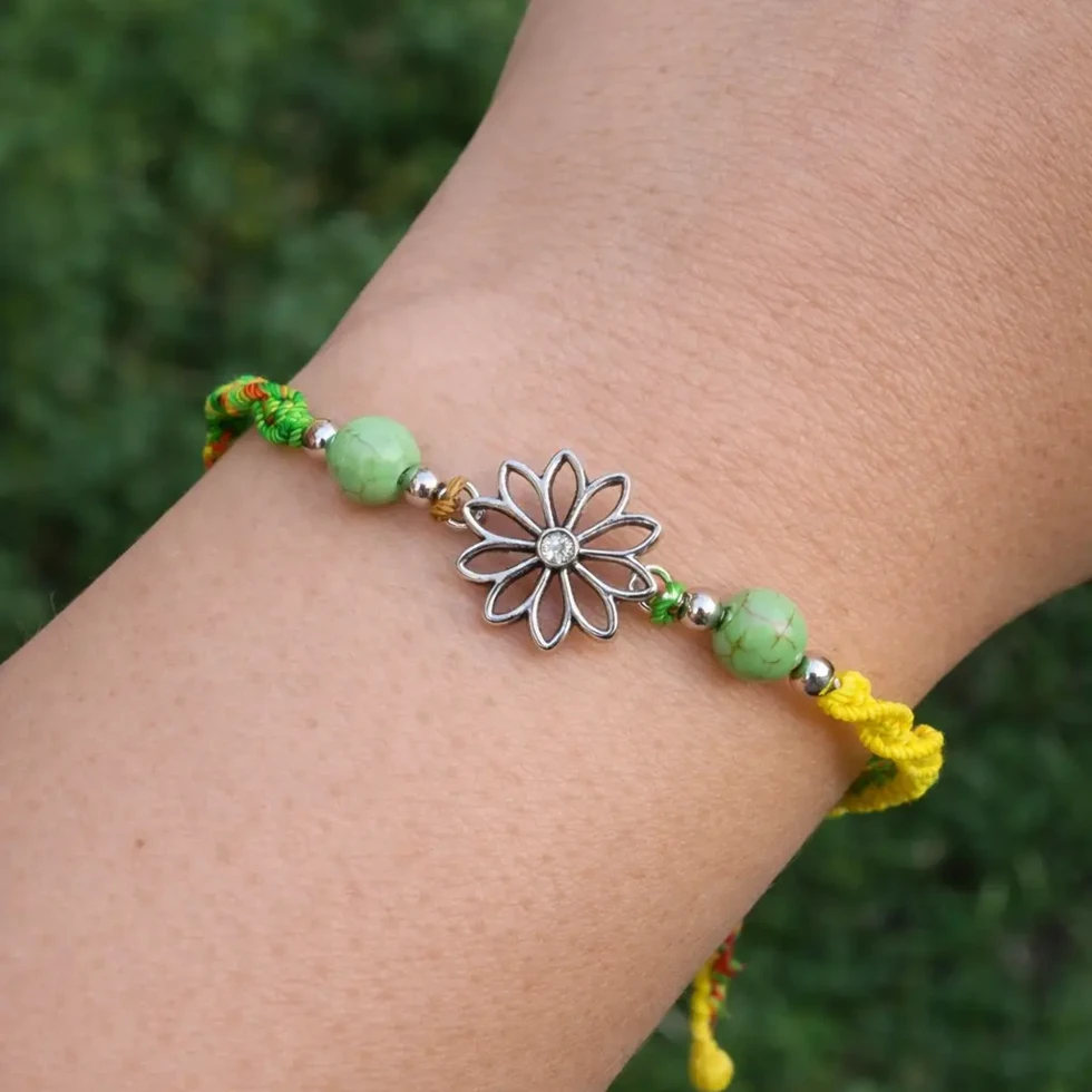 Bracelet artisanal vert et jaune avec fleur centrale porté au poignet
