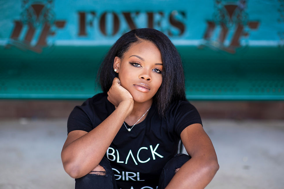 High school senior female sitting on ground in front of school bench. .