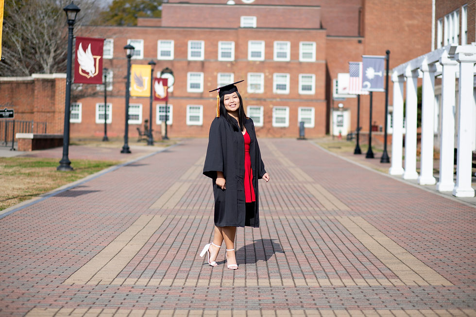 College graduate standing on Winthrop University campus wearing cap and gown.