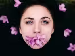 Visage de femme sur fond noir avec des fleurs d'azalées dans la bouche