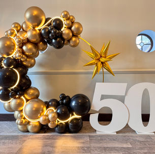 Impressive glitz black and gold balloon hoop with a neon string that was created by Confetti Party, balloon decoration company 