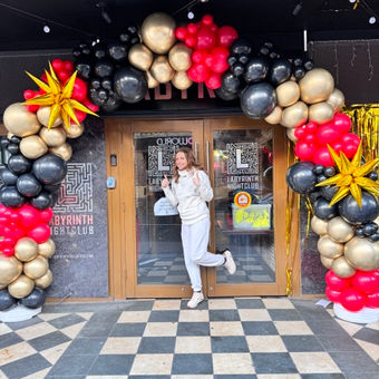 Organic balloon arch in red, black, gold colours for the entrance to the night club