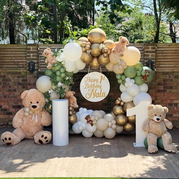 Balloon hoop in a cream, white , olive green and gold balloons with giant teddy bears sitting near